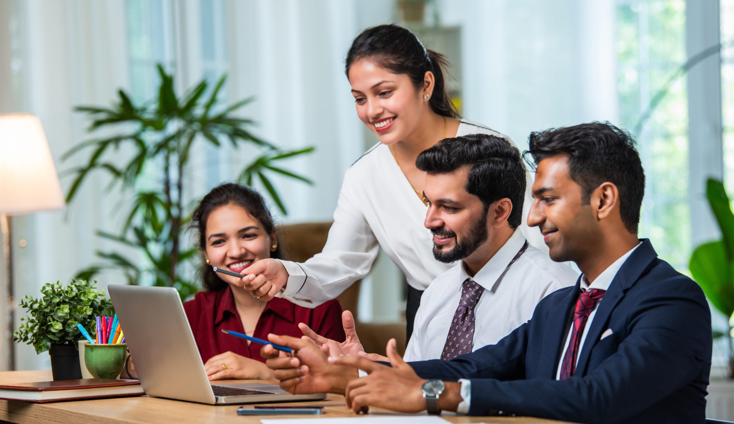 Indian asian young business professionals using laptop on desk discussing strategy